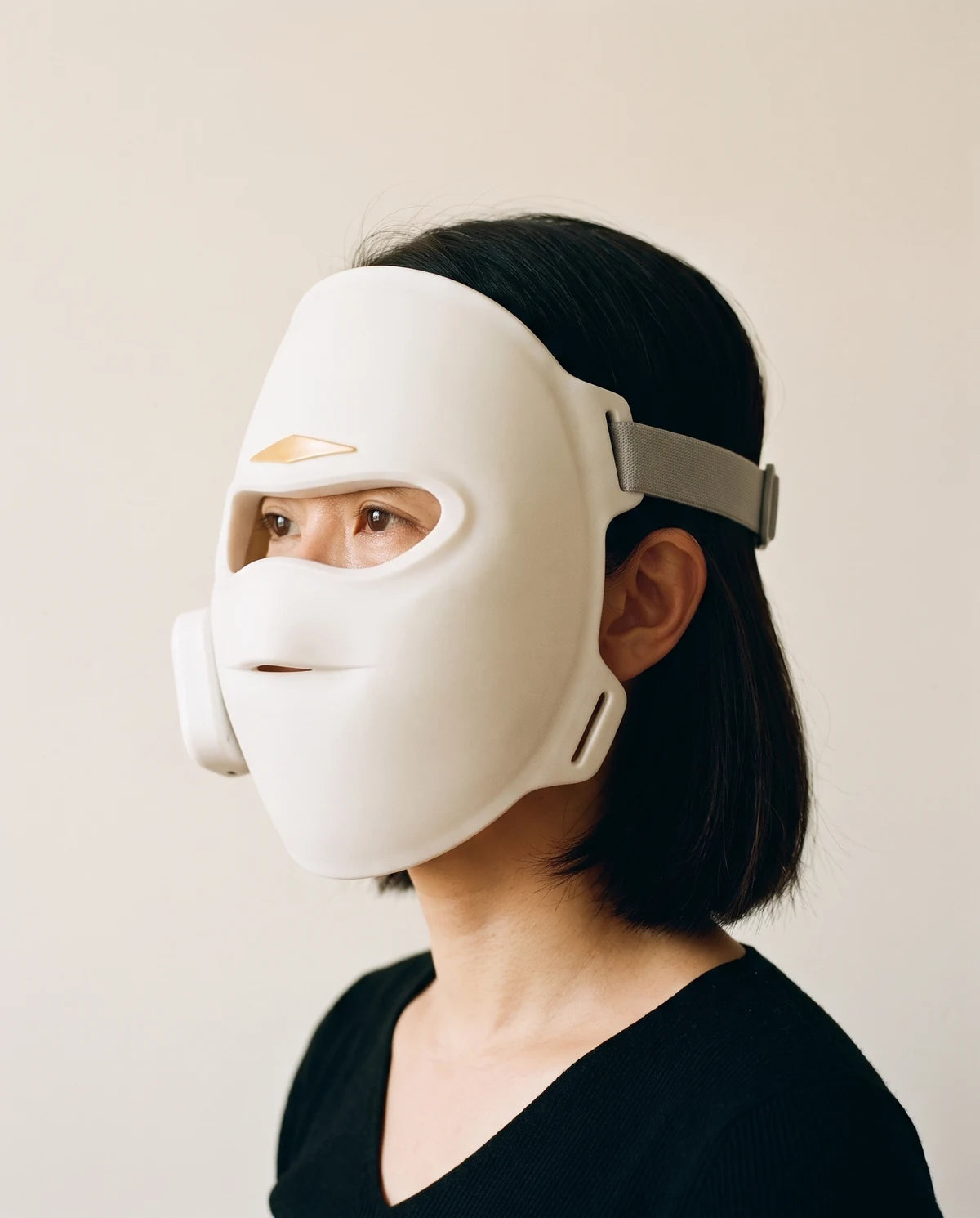 A woman wearing the mask, her eyes visible through the wide opening